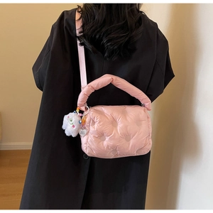 Detailed view of pink quilted puffer bag featuring plush charm and heart pendant