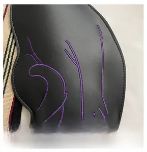 Detail of purple embroidery on black leather saddle bag with striped woven strap