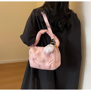Detailed view of pink quilted puffer handbag with adjustable strap and plush keychain