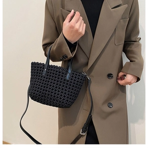 Close-up of black woven leather tote bag texture with adjustable shoulder strap