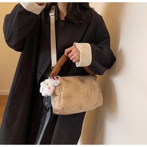 Detail of beige quilted down puffer bag with brown handle and plush monster charm
