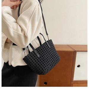 Detailed view of black woven leather bucket bag with top handle and crossbody strap