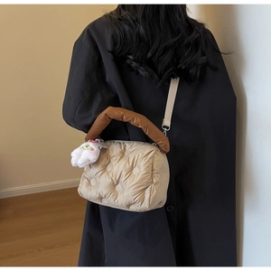 Quilted down crossbody bag with polka dot pattern and plush charm on a female model