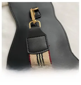 Close-up of golden metal clasp with classic beige black and red striped woven strap
