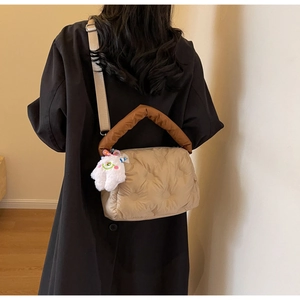 Detailed back view of a beige quilted puffer bag with a plush charm and brown handle