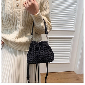 Macro detail of hand-woven black bucket bag with textured fiber pattern and drawstring closure