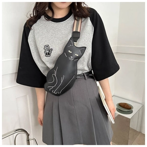 Detail of cute black cat crossbody bag with distinctive striped shoulder strap on model