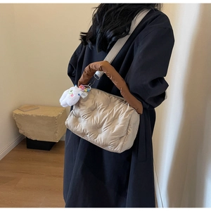 Detail of beige quilted puffer crossbody bag with brown handle and plush heart charm