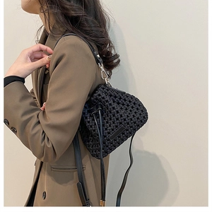Detail of black woven crossbody bucket bag texture with drawstring on a brown blazer