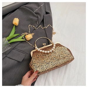 Detail of a gold sequin evening clutch featuring a metal ring handle and pearl chain