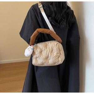 Close-up of quilted down puffer bag in champagne with plush forever charm and brown handles