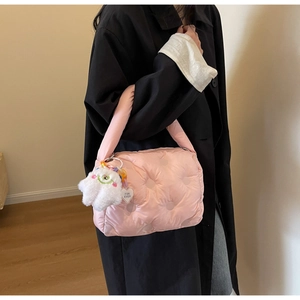 Detail of pink quilted puffer bag featuring a white plush heart charm and glossy finish