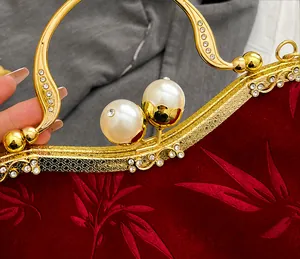 Detail of red velvet evening bag featuring leaf texture, gold frame, and pearl clasp