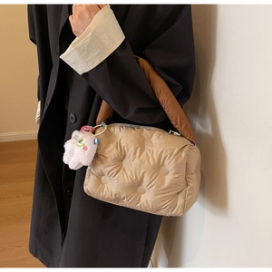 Detail of quilted down shoulder bag with brown handles and plush monster charm
