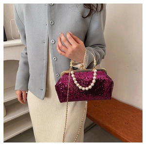 Close-up of rose red sequin handbag with pearl handle and golden metal clasp detail