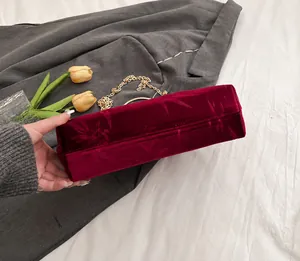 Detail of dark red velvet evening bag with bamboo leaf pattern and gold metal handle