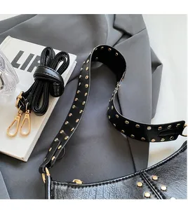 Close-up of black rivet shoulder bag with wide strap and gold hardware detail