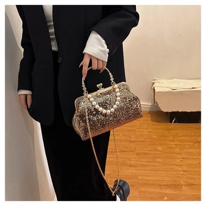 Close-up of golden sequined evening bag with pearl handle and heart-shaped lock