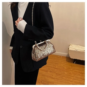 Close-up of golden sequin evening bag with pearl handle and metal chain strap
