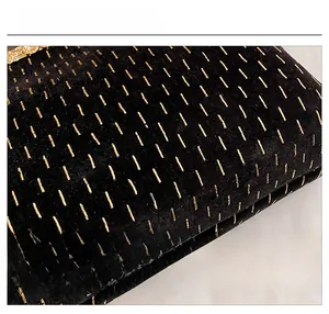 Close-up of black velvet evening bag with gold embroidery and metal hardware detail