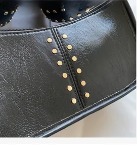 Detail of black faux leather bag featuring golden metal rivets and vertical stitching