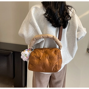 Quilted caramel down shoulder bag with beige handle and cute monster plush pendant