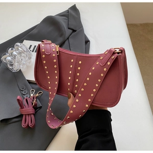Macro detail of dusky rose leather bag featuring golden studs and dual shoulder straps