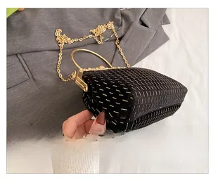 Side view of black velvet evening clutch with gold embroidery and metal ring handle