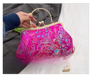 Close-up of rose red satin bag with floral embroidery and gold metal clasp closure
