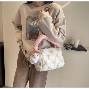 Detail of white quilted puffer bag with pink plush handle and soft doll pendant