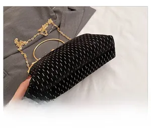 Detail view of black flocked shell bag with gold metallic stripes and metal ring handle