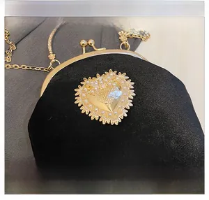 Dettaglio borsa barocca in velluto nero con cuore di perle e finiture dorate