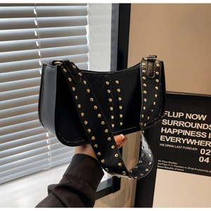 Close-up of black leather moon bag with golden studs and stylish wide shoulder strap
