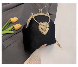 Profilo laterale della pochette barocca con charm a cuore perlato e tracolla dorata