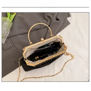 Internal view of black shell bag with gold embroidery showing space for phone and makeup