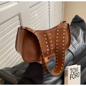 Detail of vintage brown leather bag with golden rivets on strap and body in a lifestyle setting