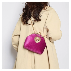 Dettaglio della borsa in velluto fucsia con cuore di perle su un trench kaki