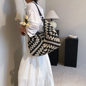 Contrast woven straw shoulder bag with black leather strap in a minimalist interior setting