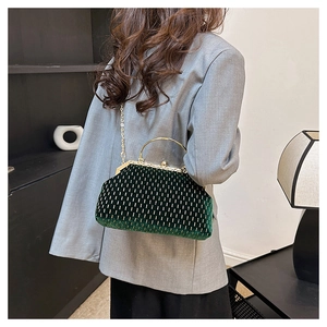 Detail of dark green velvet shell bag with gold bead dots and metal handle on a model
