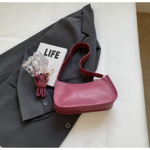 Detail view of burgundy crescent bag with gold studs and adjustable shoulder straps