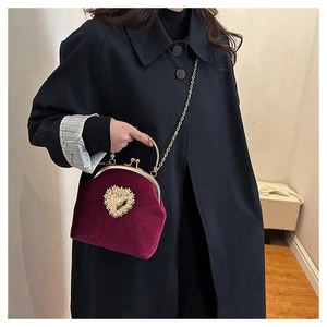 Dettaglio borsa in velluto bordeaux con cuore dorato e perle su cappotto nero
