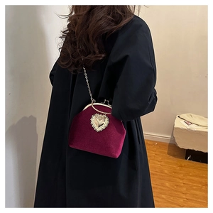 Dettaglio pochette in velluto bordeaux con cuore di strass dorato e catena barocca