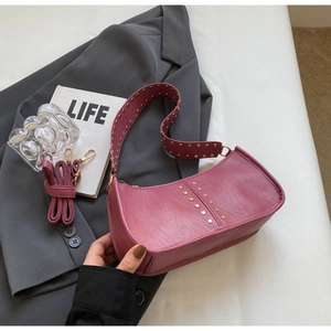 Detail of vintage studded hobo bag in dark pink leather with wide rivet shoulder strap