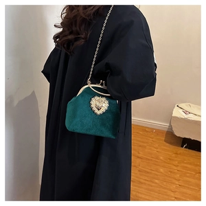 Dettaglio della borsa a conchiglia in velluto verde scuro con chiusura a cuore dorata
