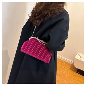 Detail of rose pink velvet evening clutch bag with gold chain strap on model