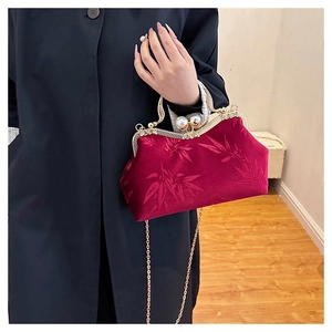 Detail of burgundy velvet shell bag with jacquard bamboo patterns and pearl clasp