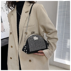 Detail of black rhinestone shell bag with elephant logo and metal chain strap on model