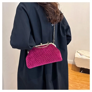 Magenta velvet shell clutch bag with gold chain worn over a dark navy trench coat