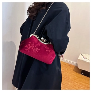 Detail of vintage burgundy velvet clutch bag with pearl clasp and gold chain strap