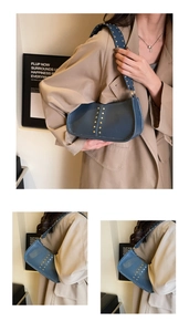 Close-up of matte blue leather underarm bag with gold rivets and wide shoulder strap